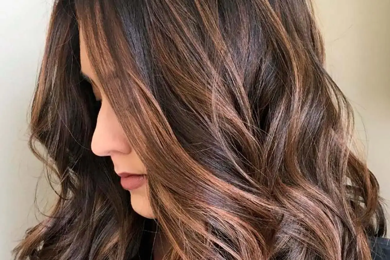 Cabello ondulado con técnica de balayage en tonos chocolate y reflejos claros para servicios de coloración